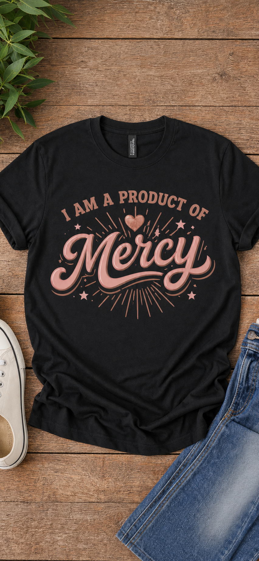 I Am a Product of Mercy graphic tee in rose gold on black, flat lay